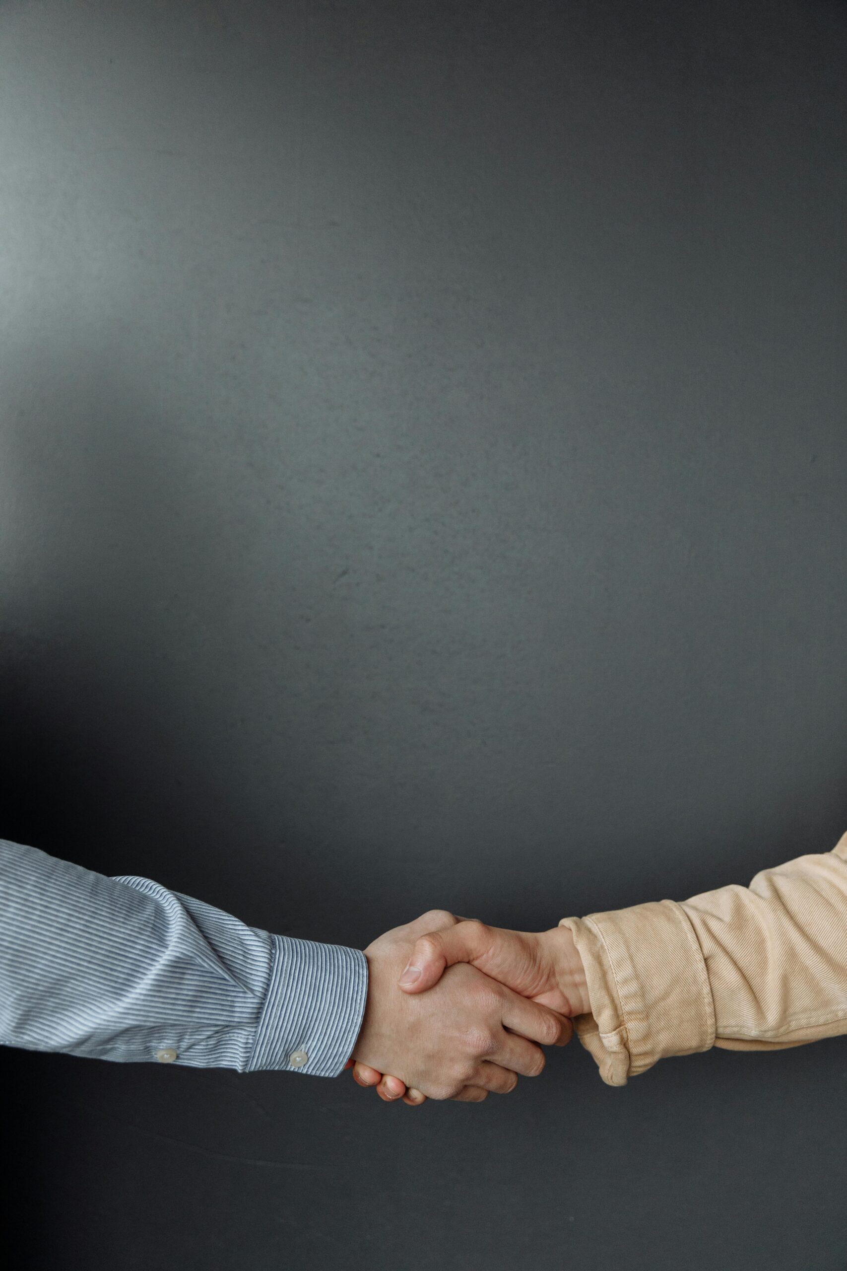 A close-up of two adults shaking hands, symbolizing agreement and partnership.
